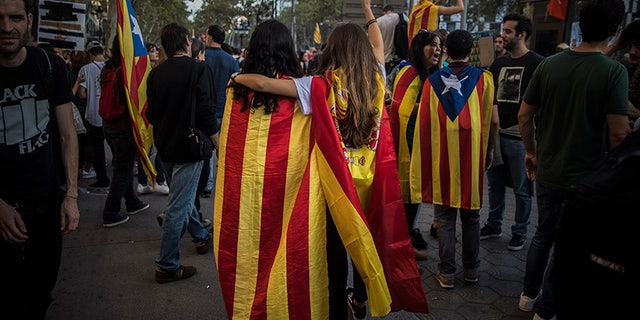 Two girls, one with a Catalan independence flag wrapped on her shoulders walks together with another one with a Spanish flag demonstrated in Barcelona in protest at what they say was police brutality during a referendum on Catalonia's secession from Spain.