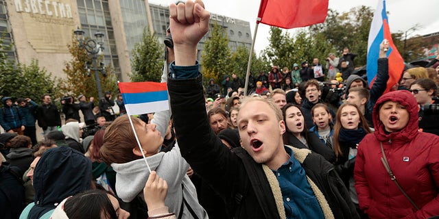 A demonstrator clenches his fist as other hold the Russian flag during a rally in Moscow, Russia, Saturday, Oct. 7, 2017. Opposition leader Alexei Navalny has worked to organize protests in support of his presidential bid across Russia on Saturday, President Vladimir Putin's birthday. (AP Photo/Ivan Sekretarev)