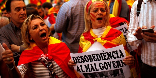 Demonstrators shout slogans, some of them holding a banner reading in Catalan "disobedience to the bad government", as they gather near a headquarters of federal police in Barcelona.