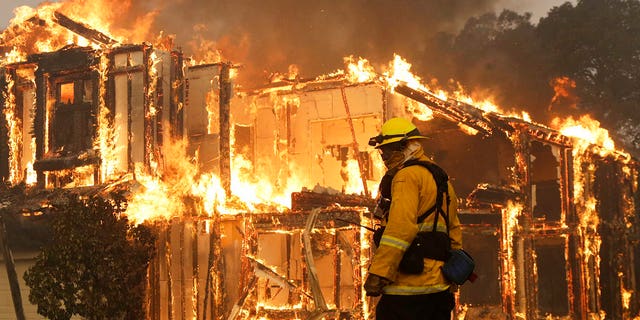 A firefighter monitors a house burning in Santa Rosa, Calif., Monday, Oct. 9, 2017.