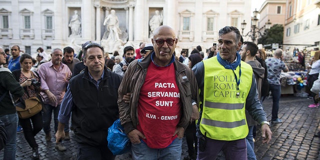 Graziano Cecchini is taken into custody after pouring red paint in the water of the Trevi Fountain, in Rome, Italy, Thursday, Oct. 26, 2017. A self-proclaimed artist, Cecchini repeated the same act that stunned the world 10 years ago, on Oct. 19, 2007. (Massimo Percossi/ANSA via AP)