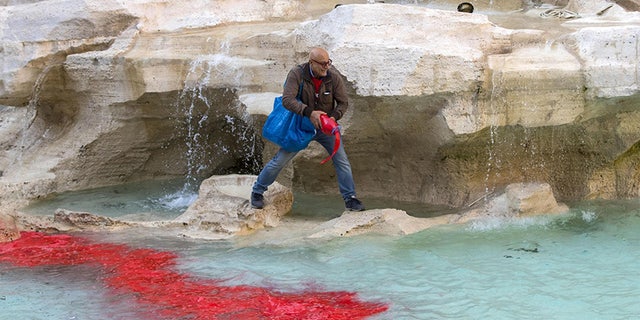 Graziano Cecchini pours red paint in the water of the Trevi Fountain, in Rome, Italy, Thursday, Oct. 26, 2017. A self-proclaimed artist, Cecchini repeated the same act that stunned the world 10 years ago, on Oct. 19, 2007. (Massimo Percossi/ANSA via AP)