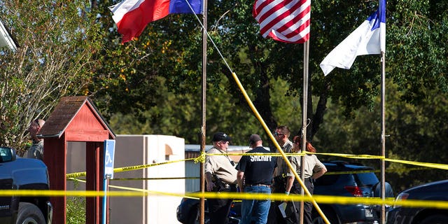 Law enforcement officials stand next to a covered body at the scene of a fatal shooting at the First Baptist Church in Sutherland Springs, Texas, on Sunday, Nov. 5, 2017.