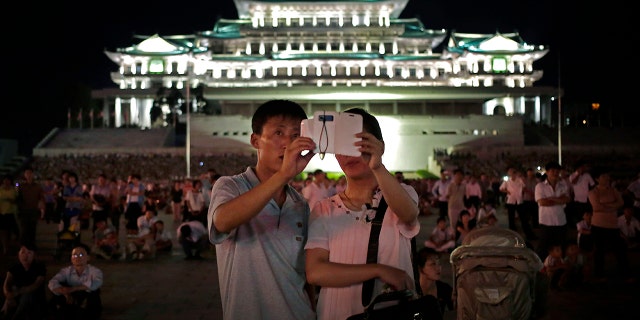 In this Sunday, July 27, 2014, file photo, a North Korean couple use a smartphone to photograph fireworks in at Kim Il Sung Square in Pyongyang, North Korea.