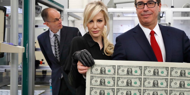 Treasury Secretary Steven Mnuchin, right, and his wife Louise Linton, hold up a sheet of new $1 bills, the first currency notes bearing his and U.S. Treasurer Jovita Carranza's signatures, Wednesday, Nov. 15, 2017, at the Bureau of Engraving and Printing (BEP) in Washington.
