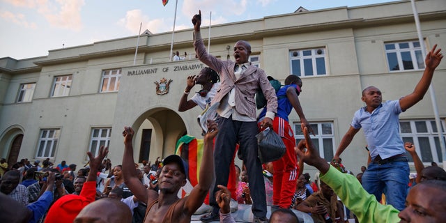 Zimbabweans celebrate outside the parliament building immediately after hearing the news that President Robert Mugabe had resigned, in downtown Harare, Zimbabwe Tuesday, Nov. 21, 2017. Mugabe resigned as president with immediate effect Tuesday after 37 years in power, shortly after parliament began impeachment proceedings against him.