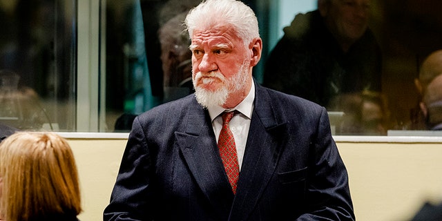 A court guard has told reporters Slobodan Praljak, 72, was alive and "receiving medical attention" after apparently taking poison in court.