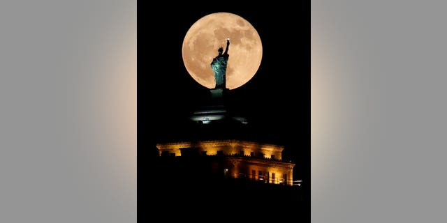 The supermoon rises in front of a replica of the Statue of Liberty sitting atop the Liberty Building in downtown Buffalo, N.Y., on Sunday.