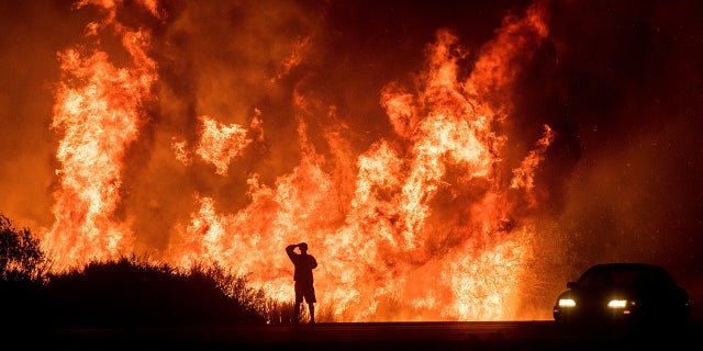 A man watches the massive flames burning in a Southern California neighborhood.