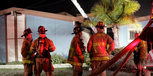 Firefighters gather outside a San Diego house where a small plane crashed, Dec. 9, 2017.
