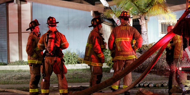 Firefighters gather outside a San Diego house where a small plane crashed, Dec. 9, 2017.