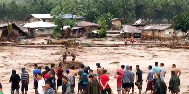 In this photo made from video by Aclimah Disumala, Friday, Dec. 22, 2017, villagers carry cross raging flood waters in Lanao del Norte, Zamboanga Pennisula, southern Philippines. A tropical storm has unleashed flash floods and set off landslides in the southern Philippines leaving dozens of people dead. (Aclimah Disumala via the AP)