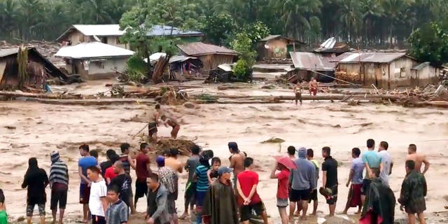 In this photo made from video by Aclimah Disumala, Friday, Dec. 22, 2017, villagers carry cross raging flood waters in Lanao del Norte, Zamboanga Pennisula, southern Philippines. A tropical storm has unleashed flash floods and set off landslides in the southern Philippines leaving dozens of people dead. (Aclimah Disumala via the AP)