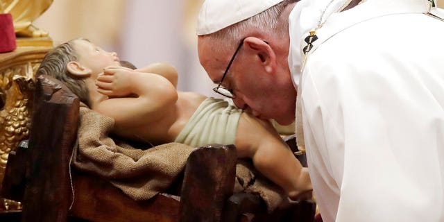 Pope Francis kisses a statue of Baby Jesus as he celebrates the Christmas Eve Mass in St. Peter's Basilica at the Vatican.