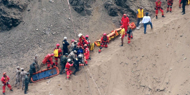 Rescue workers surround an injured man on a stretcher who was lifted up from the crash site on the beach.