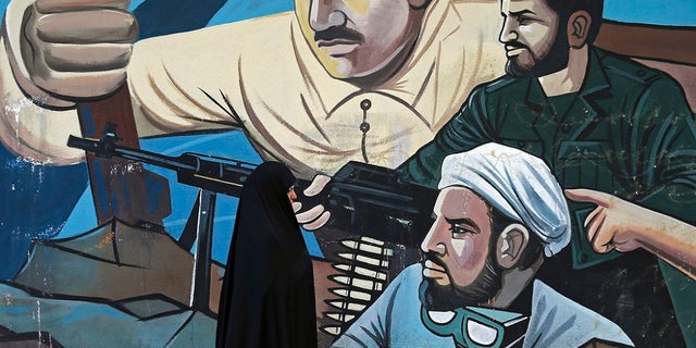 Jan 3: A woman walks past of a mural depicting members of Iran's Basij volunteer paramilitary force, in downtown Tehran