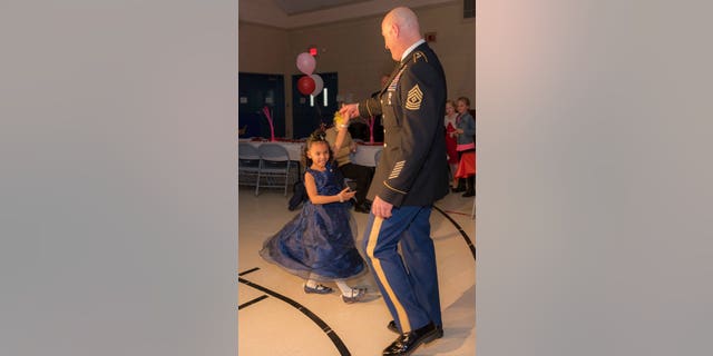 Cayleigh Hinton, daughter of Army Sgt. Terrence Hinton, dances with 1st Sgt. Joseph Bierbrodt of Sheridan, Ill., with the 933rd Military Police Company, at a father-daughter dance held at the Our Lady of Humility School