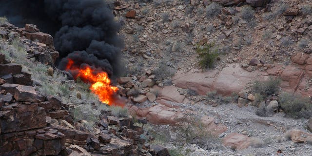 In this Saturday, Feb. 10, 2018, photo, a survivor, lower right, walks away from the scene of a deadly tour helicopter crash along the jagged rocks of the Grand Canyon, in Arizona.