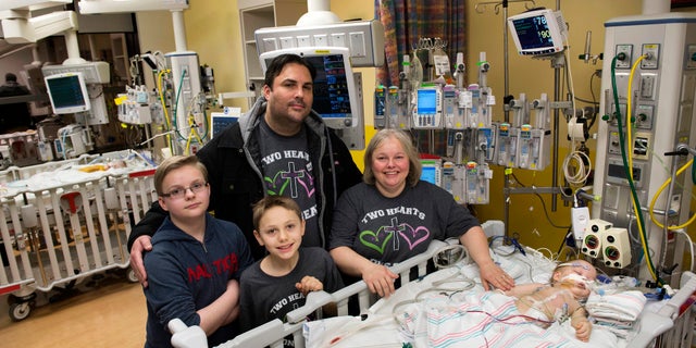 Parents Jill and Michael Richards along with their two sons, Collin and Seth, stand in the recovery room on Jan. 13 by the two beds after their twin conjoined daughters, Anna and Hope, were successfully separated.
