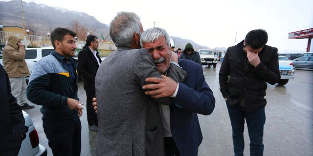 Family members of a plane crash victims weep in the village of Bideh, at the area that the plane crashed, southern Iran, Sunday, Feb. 18, 2018.