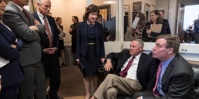 Senate Intelligence Committee Chairman Sen. Richard Burr, R-N.C., seated at center with with committee Vice Chairman Mark Warner, D-Va., right, gathers panel members before a news conference to discuss recommendations for improving the nation's election infrastructure ahead of the 2018 midterm elections, in Washington, March 20, 2018. Joining from left are Sen. Kamala Harris, D-Calif., Sen. Martin Heinrich, D-N.M., Sen. Angus King, I-Maine, and Sen. Susan Collins, R-Maine