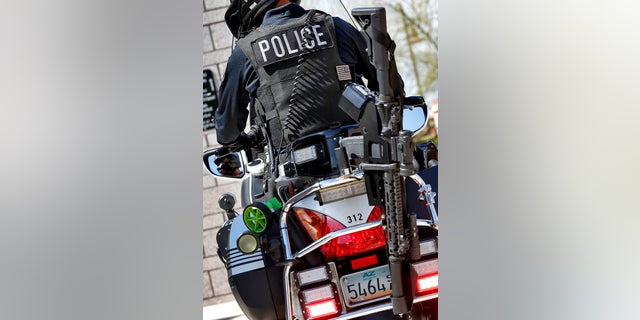 A Tempe police officer with an AR-15 rifle mounted behind him.