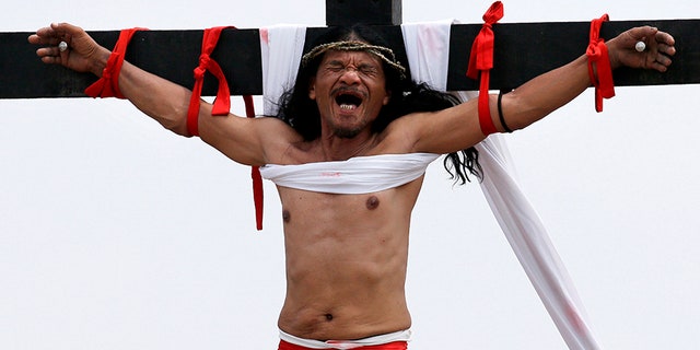 Ruben Enaje grimaces after gets nailed to the cross for the 32nd year in a row during a reenactment of Jesus Christ's sufferings as part of Good Friday rituals in the village of San Pedro Cutud, Pampanga province, northern Philippines.