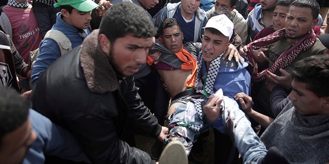 Palestinian protesters carry a wounded man during a demonstration near the Gaza Strip border.