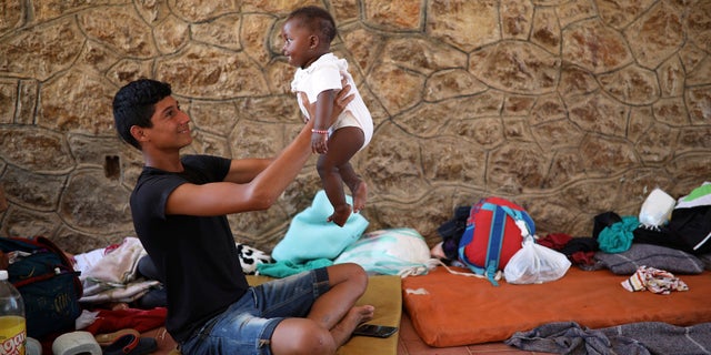 A Central American migrant plays with a baby as they rest during a few-days stop of the annual caravan.