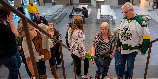 Humboldt Mayor Rob Muench, in the Broncos team jersey, along with other mourners lay down flowers on the stairs that enter to Elgar Petersen Arena, home of the Humboldt Broncos, on Saturday.