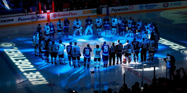 Winnipeg Jets and Chicago Blackhawks players meet at center ice for a moment of silence for the Humboldt Broncos bus crash victims before a game in Winnipeg, Manitoba, April 7, 2018.