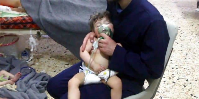 This image made from video released by the Syrian Civil Defense White Helmets shows a medical worker giving toddlers oxygen through respirators following an alleged poison gas attack.