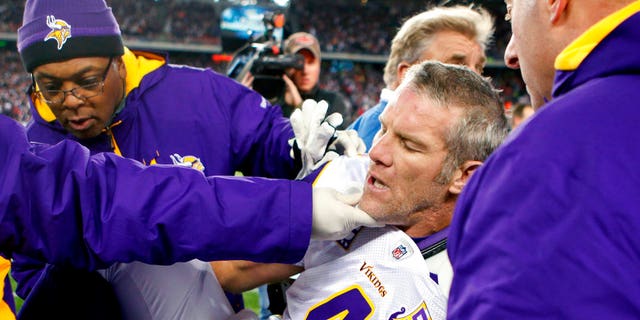 Minnesota Vikings quarterback Brett Favre, center, is helped onto a cart to be taken off the field after a hit from New England Patriots' linebacker.