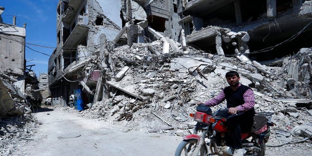 A man rides past destruction in the town of Douma, the site of a suspected chemical weapons attack, near Damascus, Syria, Monday, April 16, 2018.