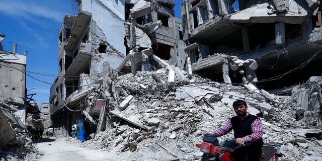 A man rides past destruction in the town of Douma, the site of a suspected chemical weapons attack, near Damascus, Syria, Monday, April 16, 2018.