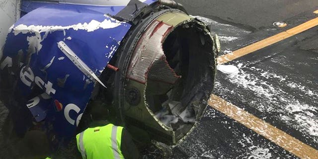 The engine on a Southwest Airlines plane is inspected while it sits on a runway at Philadelphia International Airport after making an emergency landing Tuesday.