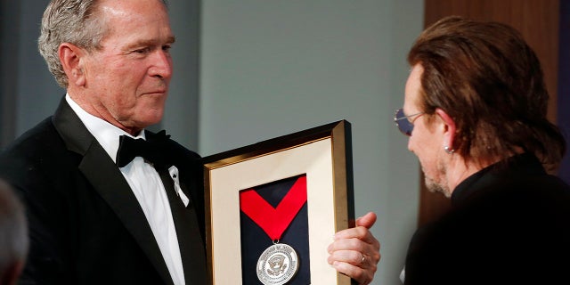 Former President George W. Bush, left, presents a medal of Distinguished Leadership to U2 musician Bono during a gala for the Forum on Leadership at the George W. Bush Institute, Thursday, April 19, 2018, in Dallas.