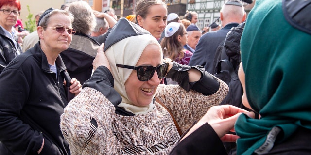 Muslim woman Samar Allaham, center, fixes the Jewish kippah on her head during a demonstration against antisemitism in Germany.