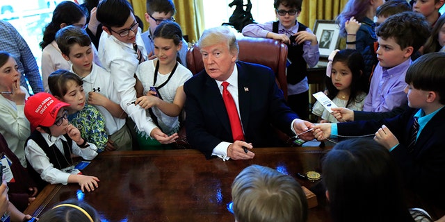 The kids crowded around the president's desk in the Oval Office for a photo.