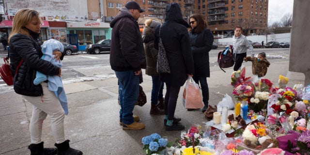 People gather at a sidewalk memorial for two children who were killed in March when they were struck by a car driven by a woman who likely had a seizure behind the wheel, in the Park Slope neighborhood of the Brooklyn borough of New York. The driver, Dorothy Bruns, was arrested at her Staten Island home on Thursday, May 3, and has been charged with manslaughter.