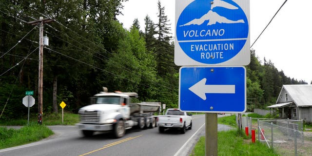 A sign under a lahar warning siren is shown as a school bus drives near Orting Middle School in Orting, Washington.