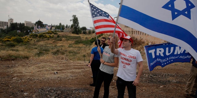Israelis hold American and Israeli flags with the new U.S. embassy in the background in Jerusalem, Monday, May 14, 2018. Israel prepared for the festive inauguration of a new U.S. Embassy in contested Jerusalem.
