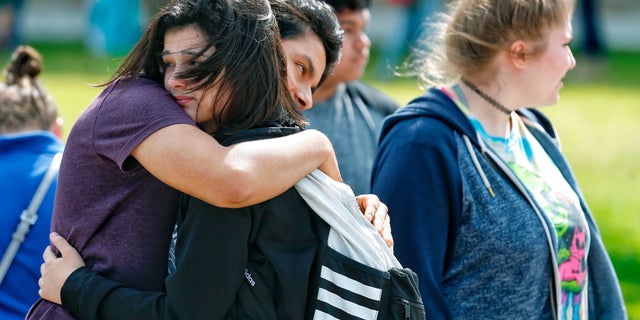 Santa Fe High School freshman Caitlyn Girouard, center, hugs her friend outside the Alamo Gym where students and parents wait to reunite following a shooting at Santa Fe High School on Friday.