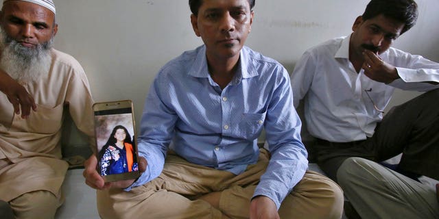 Abdul Aziz Sheikh, center, father of Sabika Sheikh, a victim of a shooting at a Texas high school, shows a picture of his daughter in Karachi, Pakistan, Saturday, May 19, 2018.
