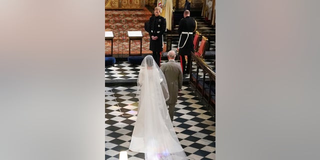 Britain's Prince Harry looks at his bride, Meghan Markle, as she arrives accompanied by Prince Charles during their wedding ceremony at St. George's Chapel in Windsor Castle in Windsor, near London, England on Saturday.