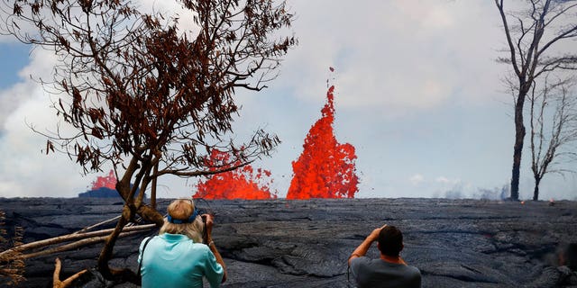 People take pictures as fissures spew lava in the Leilani Estates subdivision near Pahoa, Hawaii.