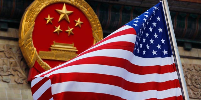 An American flag is flown next to the Chinese national emblem during a welcome ceremony for visiting U.S. President Donald Trump outside the Great Hall of the People in Beijing.