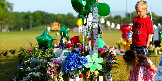 Two children look at a memorial for the Santa Fe High School shooting victims outside the school Wednesday, May 23, 2018, in Santa Fe, Texas.