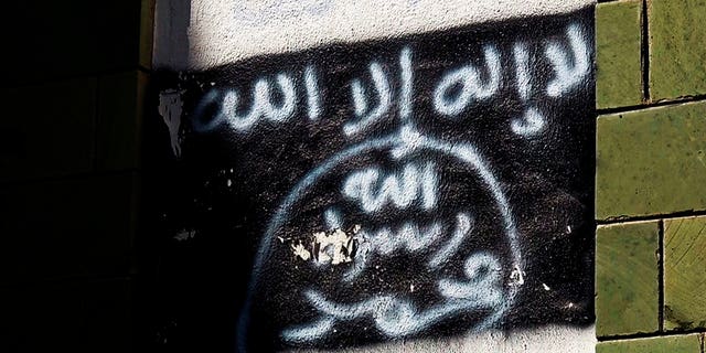 The black al-Qaida flag is sprayed on the wall of a damaged school that was turned into a religious court, in Taiz, Yemen, shown in this Oct. 16, 2017, photo. Al-Qaida fighters and other militants poured into Taiz to help defend it against Shiite rebels who have besieged it since 2015, and now the extremists are intertwined with militias financed by the U.S.-backed coalition. (AP Photo)