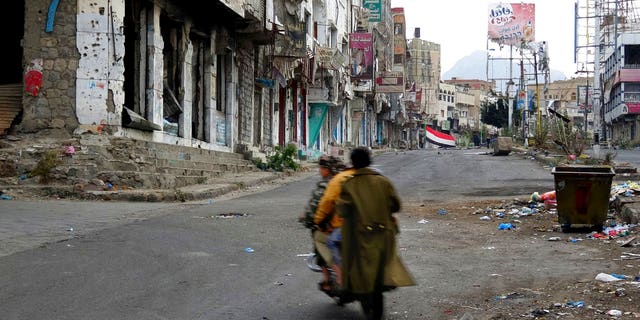 Men ride through streets wrecked by fighting in Taiz, Yemen in this Feb. 4, 2018, photo.